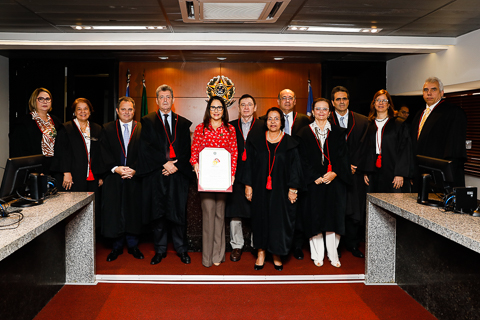 Fotografia de desembargadores, em pé, na sala do Pleno. Todos vestem toga, com exceção da presidente do TRT-MG