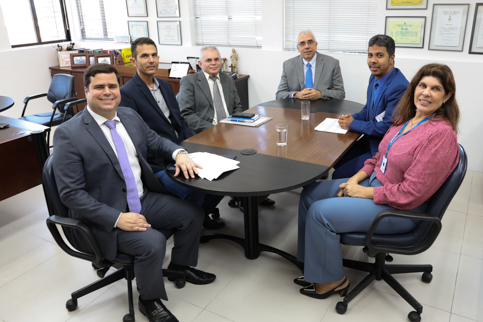 Foto de seis pessoas em volta de uma mesa de reuniões