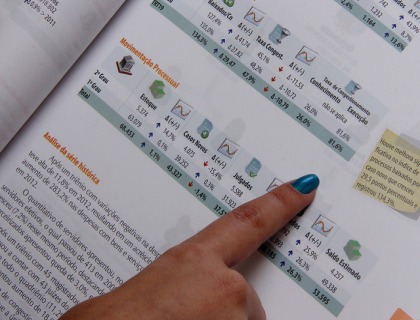 Uma mão aponta para dados em uma espécie de livro com estatísticas
