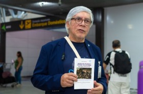 Foto magistrado segurando cartilha no saguão do aeroporto