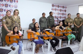 Autoridades ao lado de alunas com violão. 