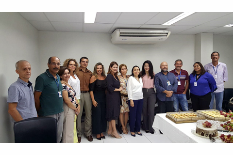Grupo de 14 pessoas dentro de uma sala, posando para foto
