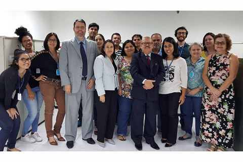 Fotografia de 17 pessoas, dentro de uma Vara do Trabalho. 