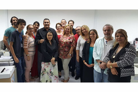 Fotografia de 15 pessoas, dentro de uma Vara do Trabalho. 