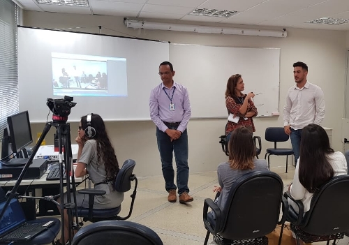 Fotografia de pessoas em uma sala de aula, participando de uma videoconferência