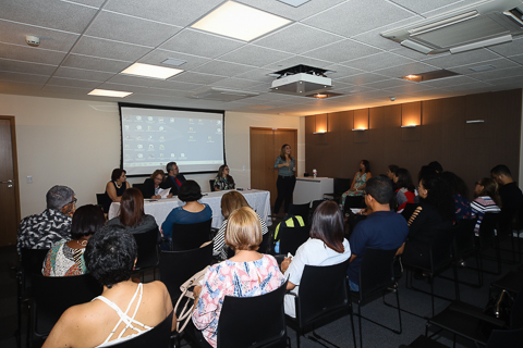 Fotografia de pessoas sentadas assistindo a uma palestra