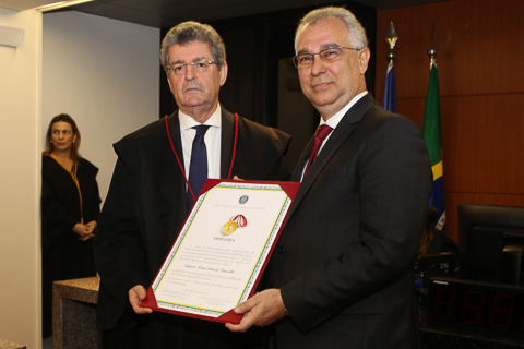 Fotografia de dois homens de terno segurando um diploma 