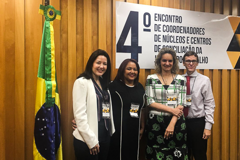 Foto dos representantes do TRT6 no evento ao lado da faixa com o nome do encontro