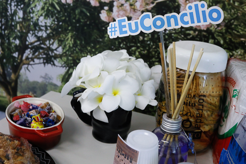 Foto de uma mesa com flores e bombons e uma placa escrito Eu Concilio