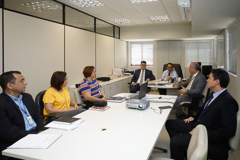 Foto dos integrantes do comitê sentados à mesa