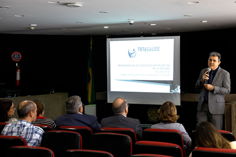 Servidor do TRT6 segurando um microfone diante da plateia em um auditório