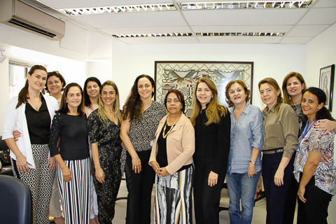 Fotografia de várias mulheres, em trajes profissionais, em pé, olhando para a câmera