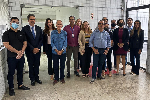Retrato de um grupo de pessoas. Elas usam trajes de trabalho e estão em pé