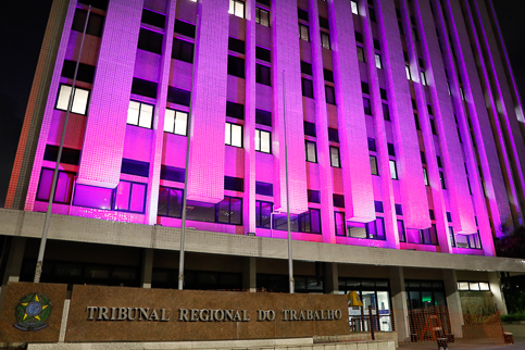 Foto do prédio-sede iluminado de rosa