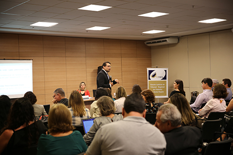 Palestrante falando para uma plateia dentro de um auditório