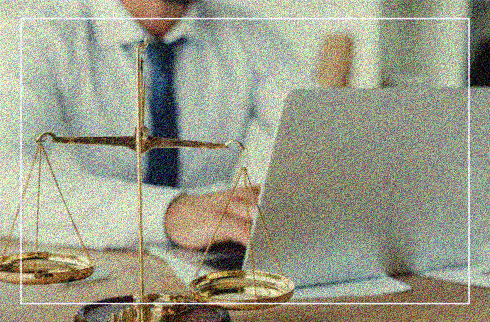 Imagem de um homem de gravata em frente ao computador. Ao lado, uma balança da justiça