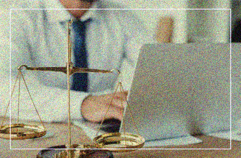 Imagem de um homem de gravata em frente ao computador. Ao lado, uma balança da justiça