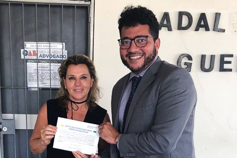 Fotografia da Desa. Maria Clara Saboya e do juiz Marcus Vinícius Oliveira segurando um certificado