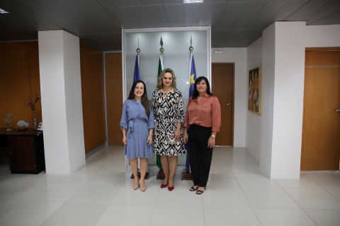 foto da presidente ladeada pelas duas servidoras empossadas. Elas estão em uma sala ampla, na frente das bandeiras do Brasil, Pernambuco e Recife
