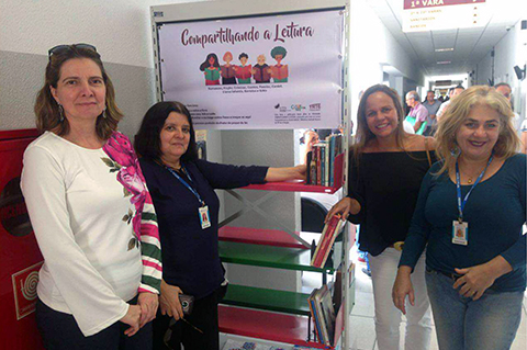 Fotografia de quatro mulheres próximas a uma estante de livros