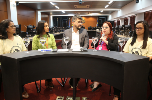 Foto das palestrantes e do mediador na mesa do evento