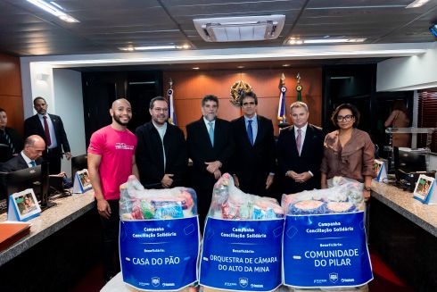 foto cinco pessoas em pé à frente donativos arrecadados