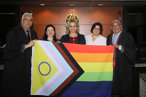 fotografia de três magistradas e dois magistrados segurando a bandeira da diversidade
