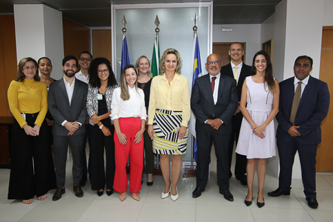 Retrato de várias pessoas em trajes formais, em pé, dentro da sala da Presidência