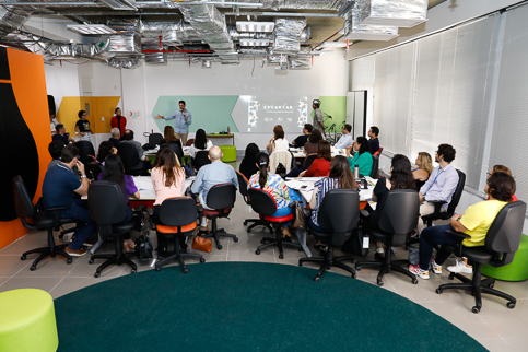 Adultos sentados em uma sala, assistindo uma aula