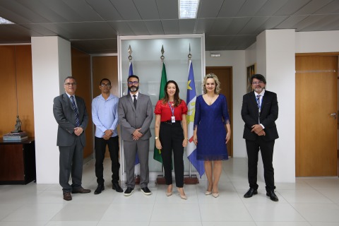 Foto de seis pessoas, em trajes profissionais, em pé e olhando para câmera