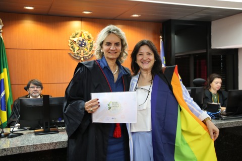 Foto da juíza Ana Freitas entregando uma carta para a desa. Nise Pedroso