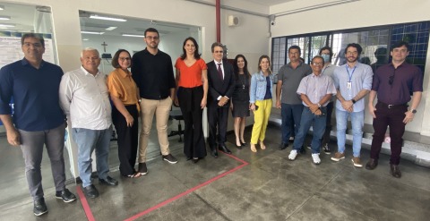 Fotografia da equipe da 1ª VT de Caruaru e da Correição. As pessoas estão em pé, na frente de uma porta de vidro