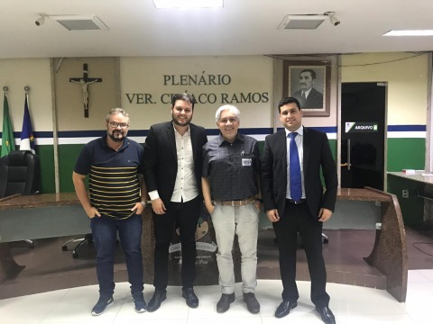 Fotografia de 4 pessoas posando para a câmara, dentro de um auditório. Na parede ao fundo é possível ler &quot;Plenário Vereador Ciríaco Ramos&quot;