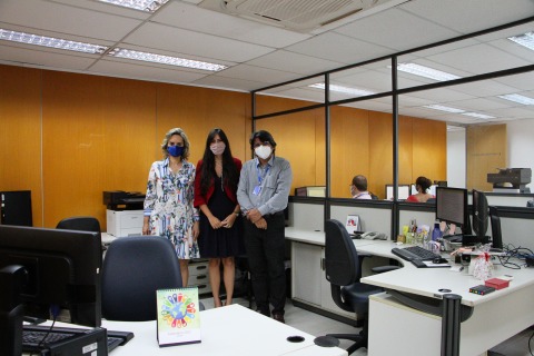 Fotografia de três pessoas em uma sala de trabalho