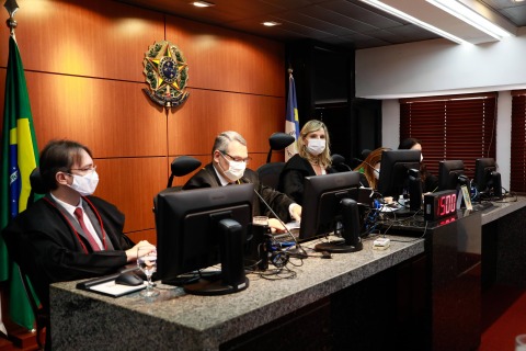 Foto da bancada do Pleno - autoridades em trajes formais, mexendo no computador