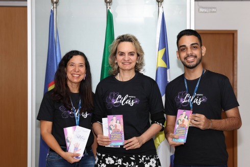 Fotografia de três autoridades com uma camisa preta escrita Agosto Lilás