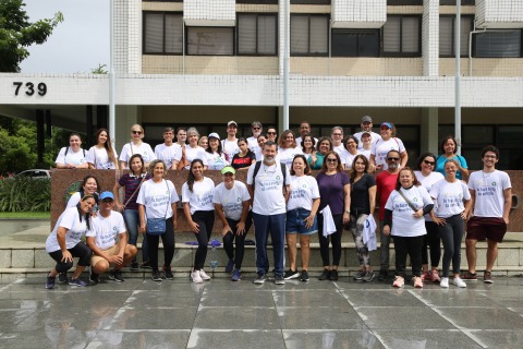 Foto do grupo da caminhada em frente ao prédio sede do Tribunal. As pessoas estão em pé e usam camisas brancas 