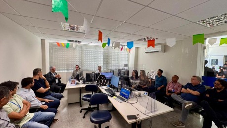 Na fotografia, aparece um grupo de adultos, reunidos numa sala de audiência