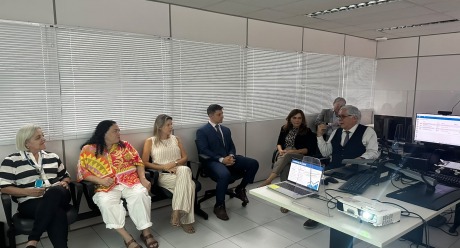 Na foto, aparecem 7 adultos sentados numa sala de audiências