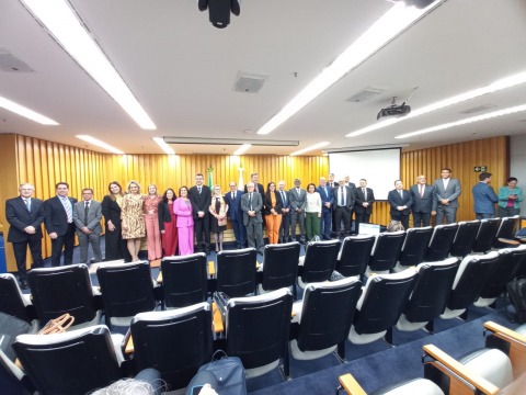 Foto de várias pessoas em pé, no palco de um auditório