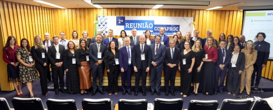 Foto mostra cerca de 30 pessoas, homens e mulheres, em pé, lado a lado, posando para a foto em um auditório