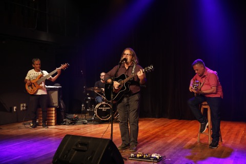 fotografia de uma banda tocando no palco de um teatro