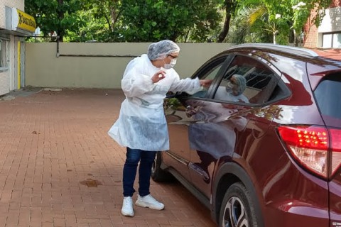 Enfermeira falando com uma pessoa dentro do carro