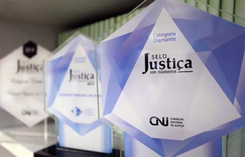 Fotografia de três placas de vidro em formato hexagonal, que simbolizam o prêmio Selo Justiça em Números