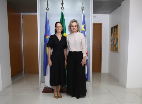 foto da desembargadora Nise Pedroso e da servidora Camila de Amorim em pé, na frente das bandeiras de Recife, Pernambuco e Brasil