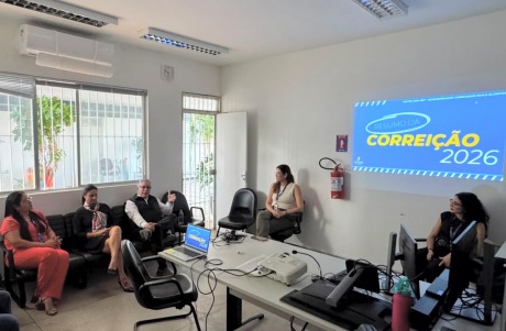 Na foto, aparecem oito adultos sentados na sala de audiências de uma Vara