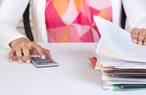 Mulher com pilhas de papeis e calculadora