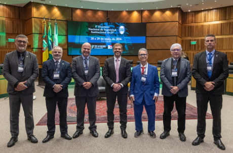 Na foto, sete homens perfilados num auditório