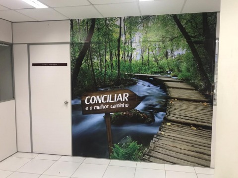 Fotografia de um papel de parede com imagem de uma ponte no meio de uma floresta e uma placa escrita &quot;Conciliar é o melhor caminho&quot;