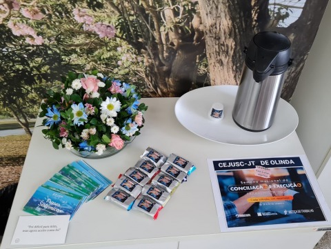 Fotografia de uma mesa decorada com flores, cartões coloridos e uma garrafa de café